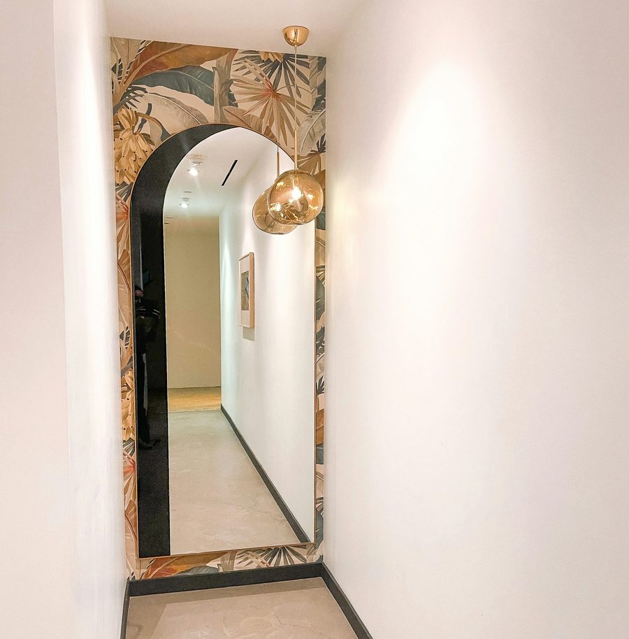 Hallway with an arched doorway, patterned wallpaper and a warm brass pendant light