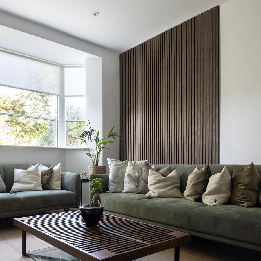Living room with a dark textured feature wall, sage green sofas and warm wood accents