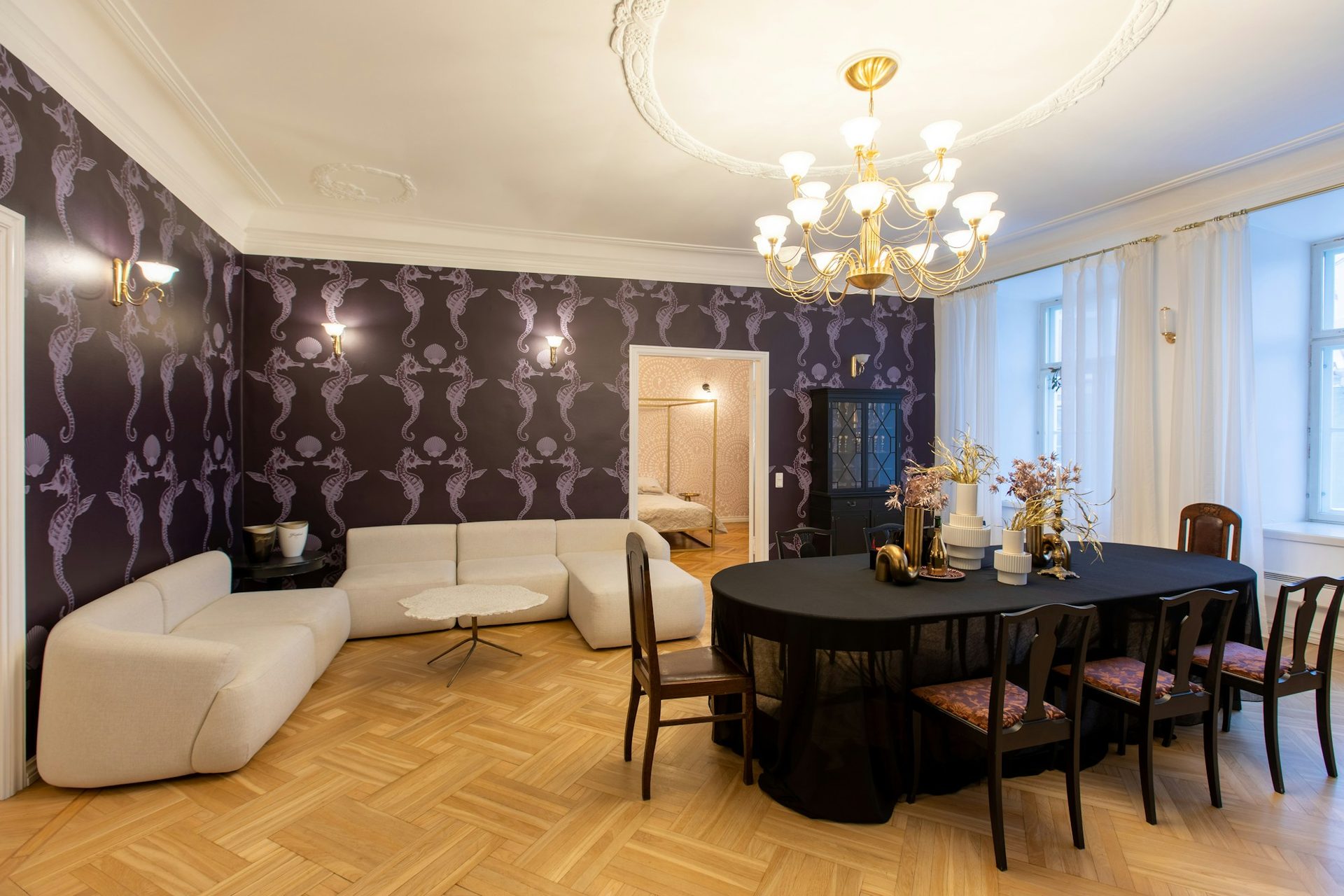 Elegant residential salon with deep aubergine damask wallpaper, a crystal chandelier and herringbone parquet floor