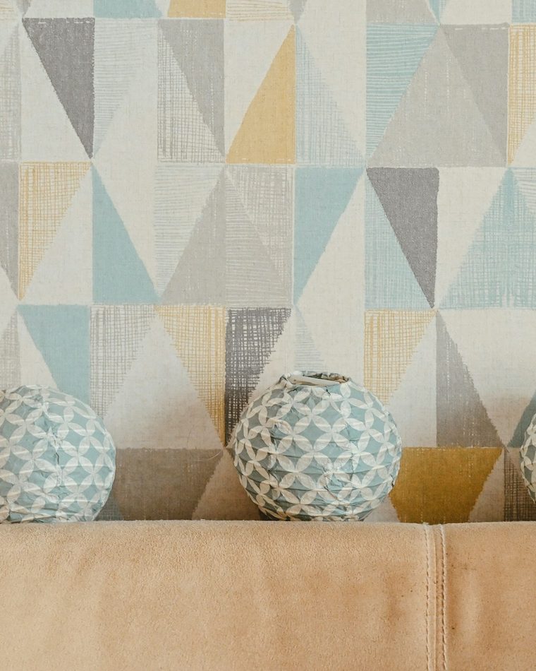 Geometric wallpaper of pastel triangles in muted blue, gold and grey